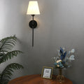 RAVENHALL ONE-BULB BLACK AND GOLD WALL LIGHT WITH WHITE LINEN SHADE