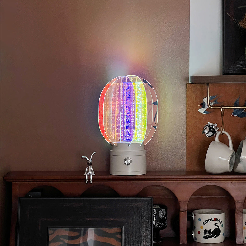 1. "VIVIENNE RAINBOW METAL TABLE LAMP"  
   A vibrant blend of colors and artistic design, this aluminum table lamp radiates warmth and creativity with its unique LED illumination.

2. "HAMPSTEAD ARTISANAL RAINBOW LAMP"  
   A striking fusion of color and